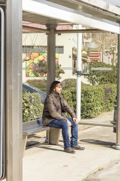 Man sitting on bench on bus stop