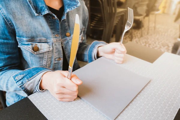 Hungry woman holding knife and fork, waiting for food, food or restaurant concept, warm light tone