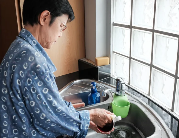 Thai woman cleaning cups at the kitchen sink