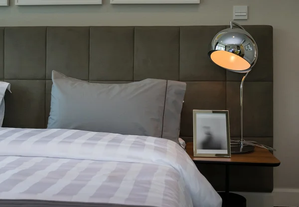 Metal desk lamp and grey pillow on bed