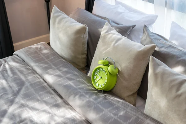 Modern bedroom with green alarm clock and pillows on bed