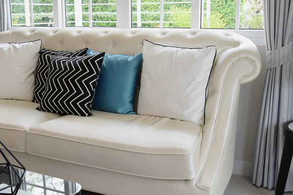 White and blue pillows on a white leather couch in vintage living room
