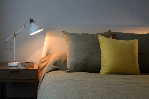 Cozy bedroom interior with pillows and reading lamp on bedside table