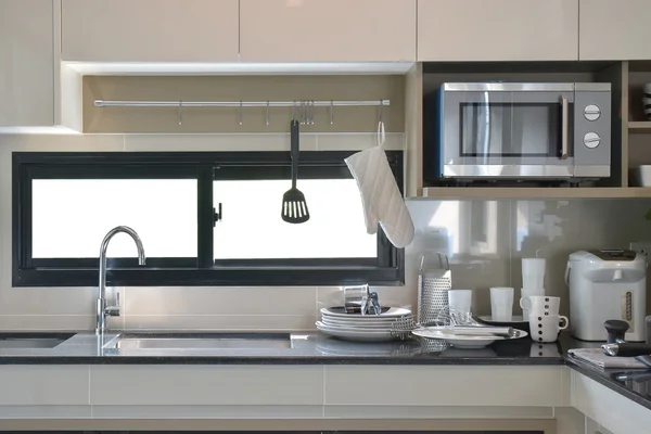 Ceramic ware and utensils setting up next to sink in modern kitchen