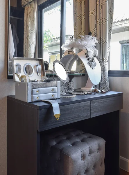 Table mirror,sunglasses,jewelry and makeup brushes on a black dressing table