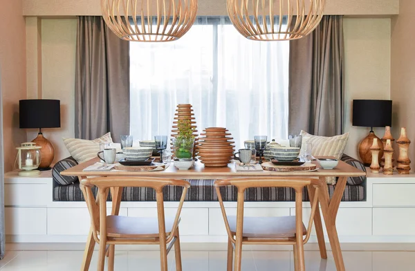 Dining wooden table and comfortable chairs in modern home with elegant table setting