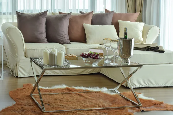 Aroma candles and wine glasses on the table with beige sofa and deep brown pillows in modern living room