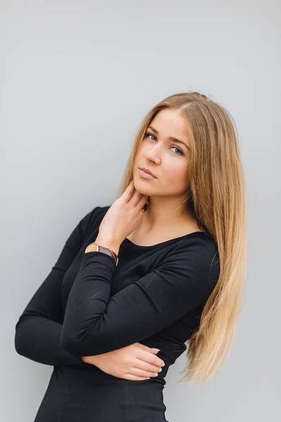 Blonde young woman standing behind the wall and posing ti camera