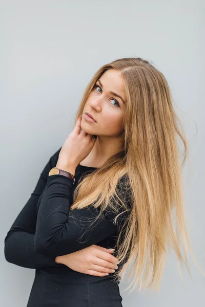 Blonde young woman standing behind the wall and posing ti camera