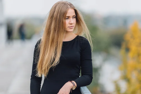 Blonde young woman standing behind the wall and posing ti camera