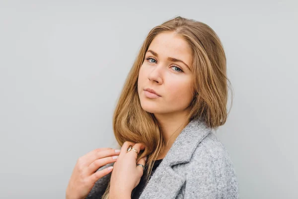 Blonde young woman standing behind the wall and posing ti camera