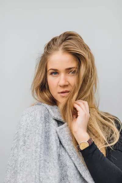 Blonde young woman standing behind the wall and posing ti camera