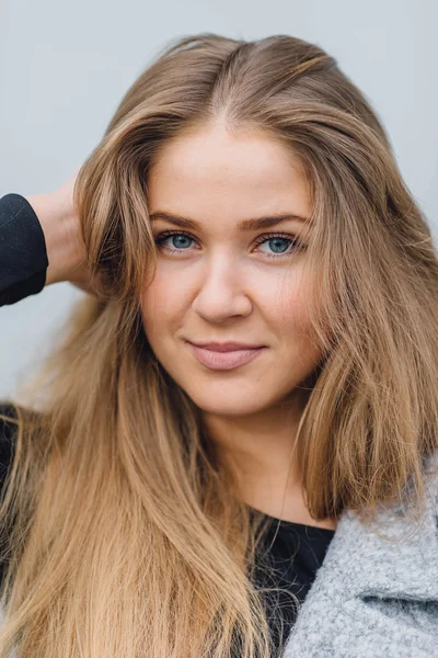 Blonde young woman standing behind the wall and posing ti camera