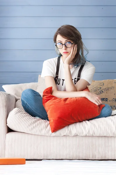 Sad young student sitting on a couch and hugging a pillow. She failed the exam.