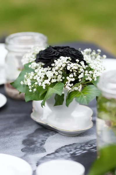 Elegantly decorated wedding table in the garden. Holiday, full of romance and love. White dishes standing on a black tablecloth