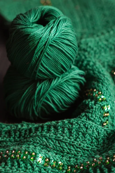 Two balls of deep green yarn and green beaded scarf.