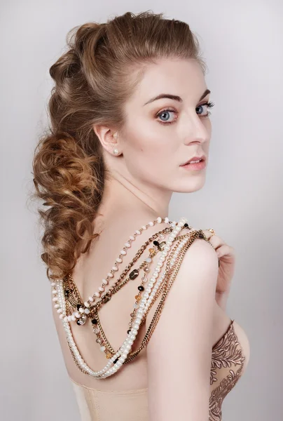 Young beautiful dark blonde woman in a gold and pearls necklace