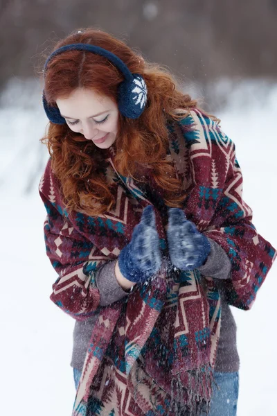 Portrait of attractive young curly red-haired woman in blue gloves and headphones