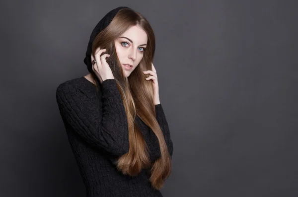 Young beautiful woman with long, gorgeous dark blond hair. She is dressed in warm gray knit dress