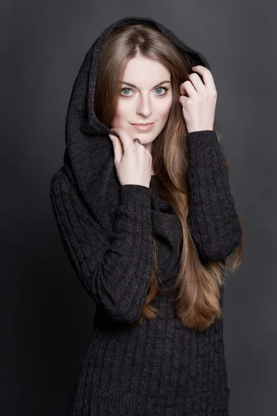 Oung attractive woman with long, gorgeous dark blond hair and large blue eyes. She is dressed in warm gray knit dress with a hood