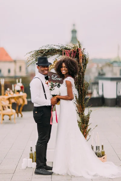 Happy african wedding couple smiling and holding hands on the rooftop