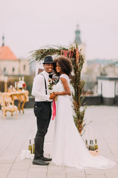 Black wedding couple posing for camera on the rooftop and smiling