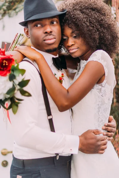 Sweet black bride dreamily puts head on shoulder of her groom