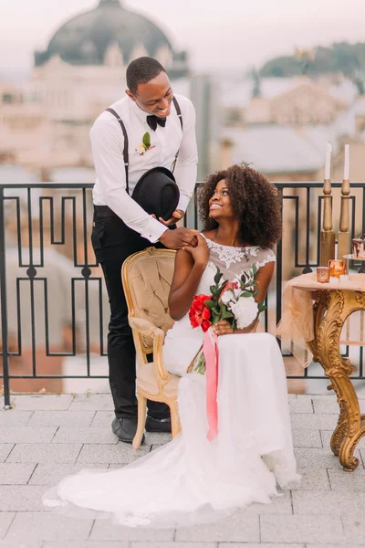 Happy black bride and groom smiling and holding hands on the terrace. Wedding day