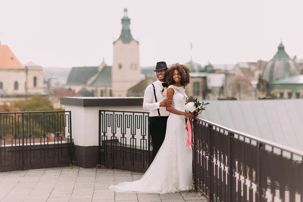 African wedding couple on the rooftop. Amazing european Lviv architecture on background