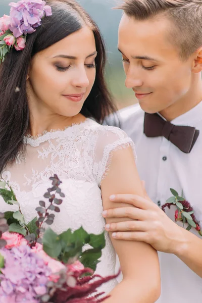 Beautiful wedding couple with flowers in hands close up