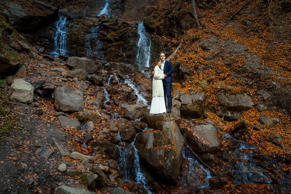 Romantic wedding couple. Waterfall on background. Honeymoon in the mountains