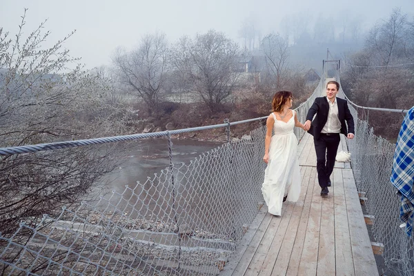 Happy wedding couple walking and laughing on the wooden bridge. Honeymoon at mountains