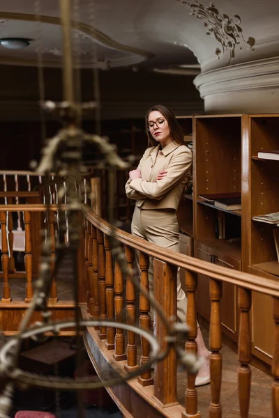 Beautiful young stylish lady standing on balcony in the vintage library