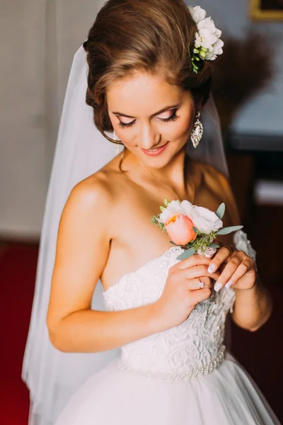 Beauty bride in bridal gown with hairstyle and bouquet indoors.