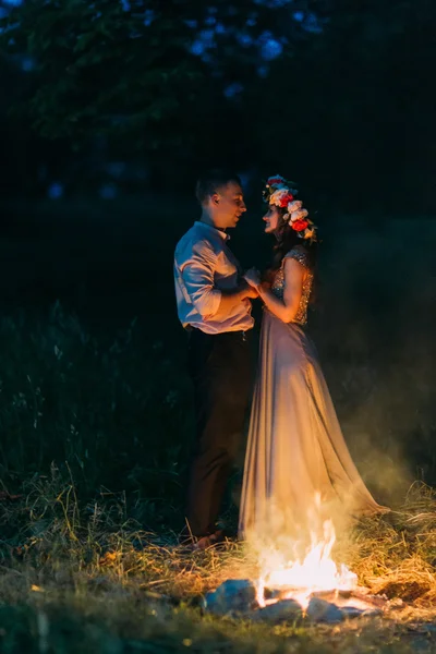 Portrait of a beautiful young couple about to kiss near fire in the night