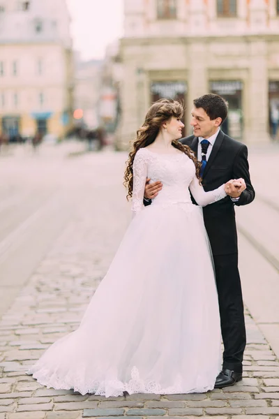 Full length portrait of bride and groom looking at each other on ancient street