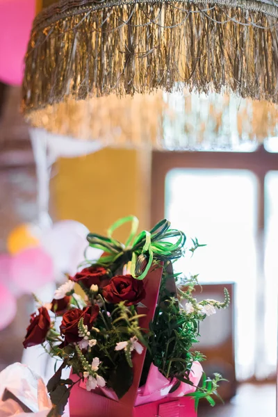 Beautiful long stem red roses with gift and postcard on the table