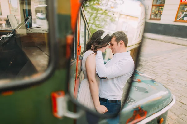 Reflection of kissing pretty young woman wearing floral headband and handsome man in the rearview mirror