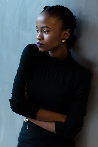 Portrait of a serious african or black american woman with arms folded standing over gray background and looking away