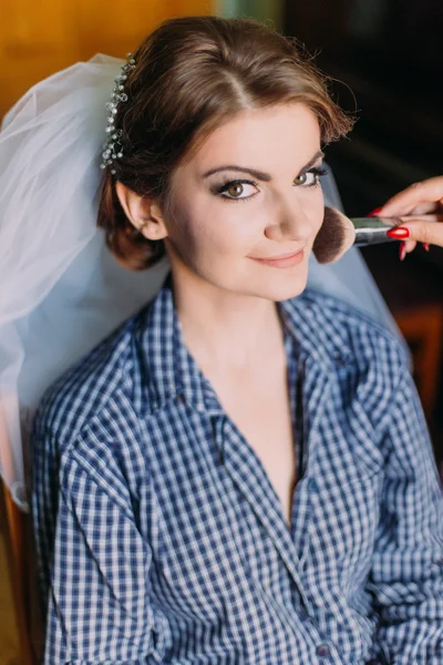 Marriage day moment. Applying make-up for beautiful young bride in dressing room before ceremony