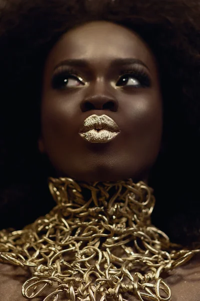 Close-up surreal portrait of majestic african american female model with gold glossy makeup. Fashion concept