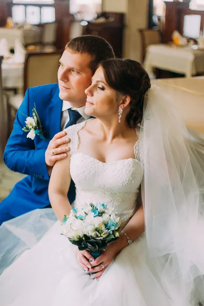 Loving stylish dressed groom gently holding his new wife in beautiful white dress