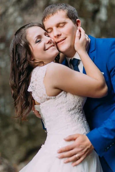 Closeup portrait of happy groom hugging with his bride. Rough blurry background