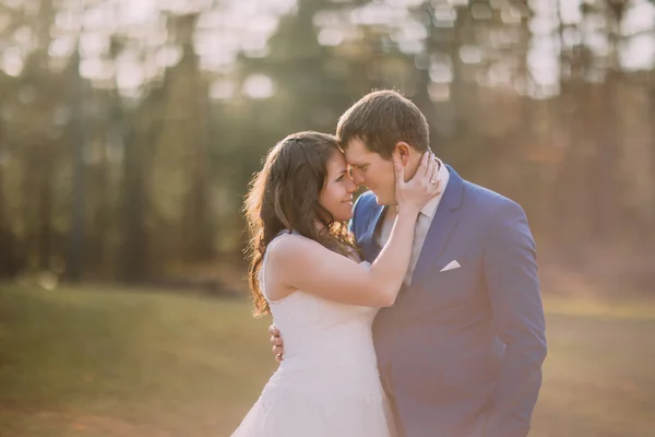 Romantic wedding couple outdoors. Happy bride going to kiss her groom. Warm washed out matte style