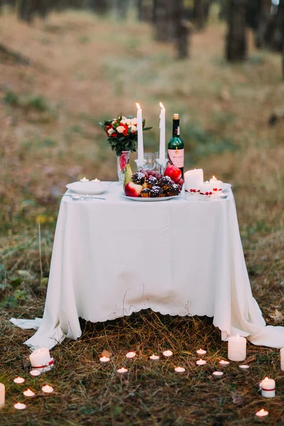 Cute table with many burning candles for romantic dinner at the autumn forest