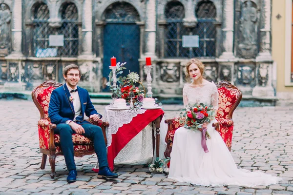 Happy newlyweds sitting on the romantic table for two and happily smiling