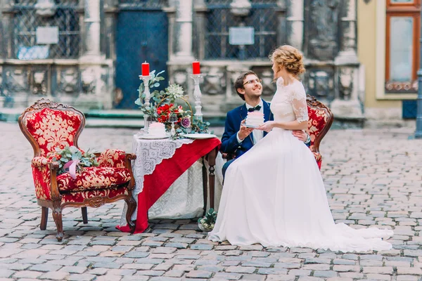 Charming bride sitting on knees of her groom and happily smiling