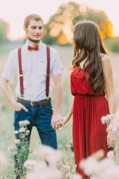 Sensual young happy couple walking in the beautiful summer field at sunset.