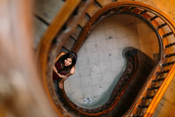 Beautiful brunette model girl posing on winding spiral staircase in an old Lviv house. Top view