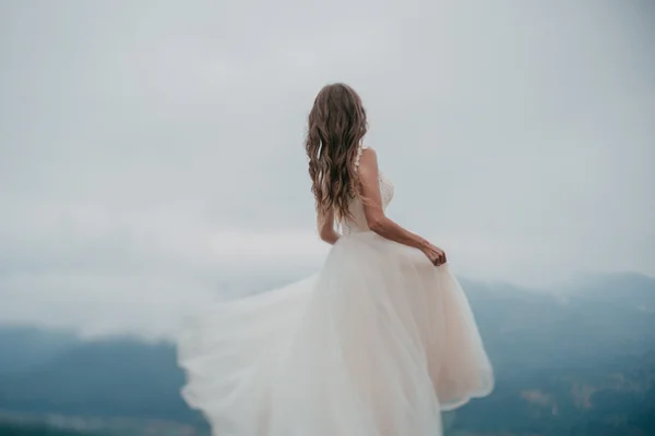 Beautiful bride in white dress posing on the mountain